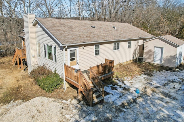 back of property featuring a deck, central AC unit, and a shed