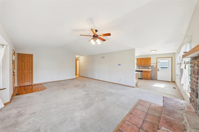 unfurnished living room featuring light carpet, vaulted ceiling, and ceiling fan