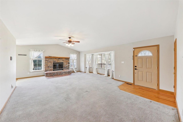 unfurnished living room with lofted ceiling, ceiling fan, a fireplace, and a healthy amount of sunlight