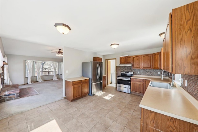 kitchen featuring sink, ceiling fan, appliances with stainless steel finishes, decorative backsplash, and light colored carpet