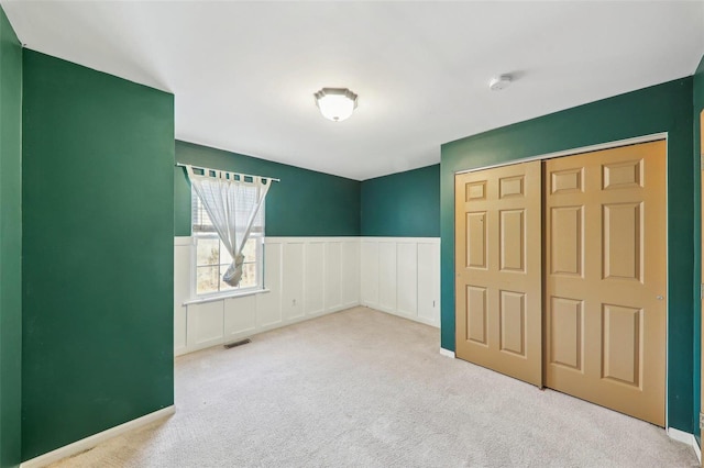 unfurnished bedroom featuring light colored carpet and a closet