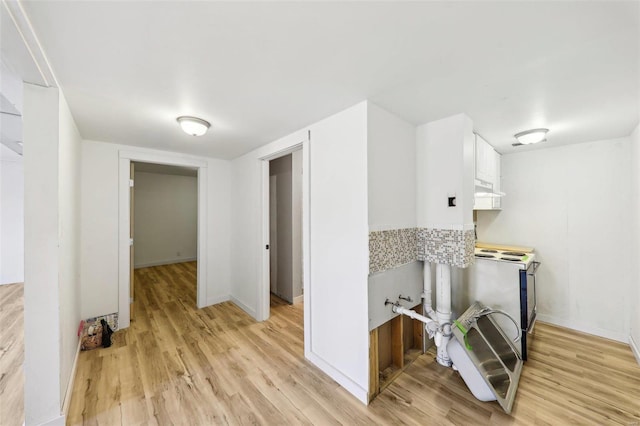 kitchen with white cabinetry, light hardwood / wood-style floors, and stove