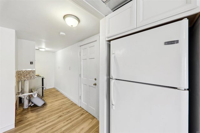 kitchen with white cabinetry, light wood-type flooring, and white fridge