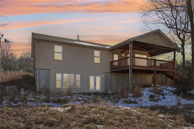 snow covered back of property with a wooden deck