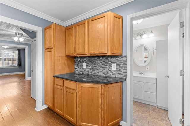 kitchen with tasteful backsplash, sink, ceiling fan, crown molding, and light wood-type flooring