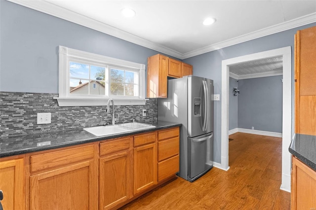 kitchen featuring sink, ornamental molding, light hardwood / wood-style floors, stainless steel fridge with ice dispenser, and decorative backsplash