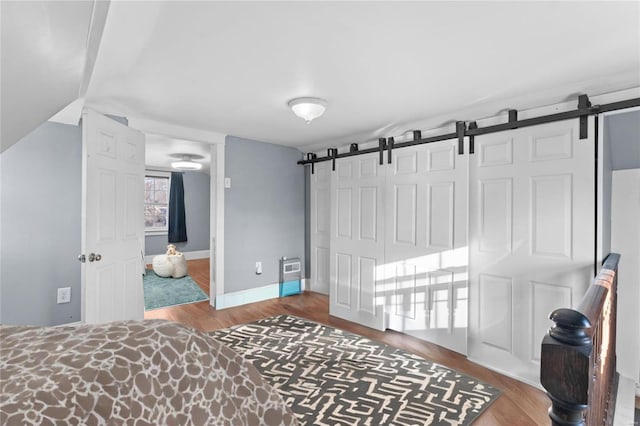 bedroom with wood-type flooring, a barn door, and a closet