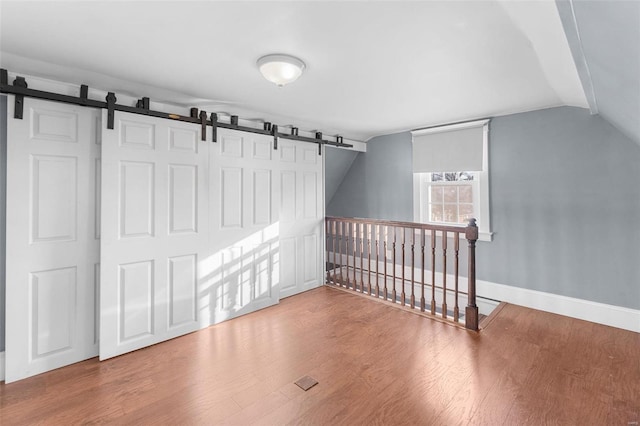 bonus room featuring lofted ceiling, wood-type flooring, and a barn door