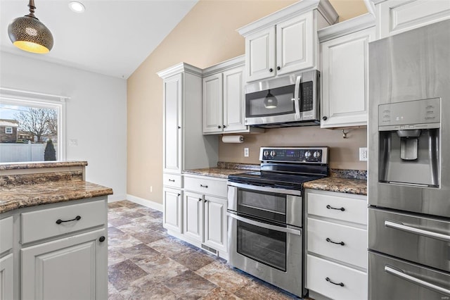 kitchen with white cabinets, dark stone countertops, lofted ceiling, and appliances with stainless steel finishes