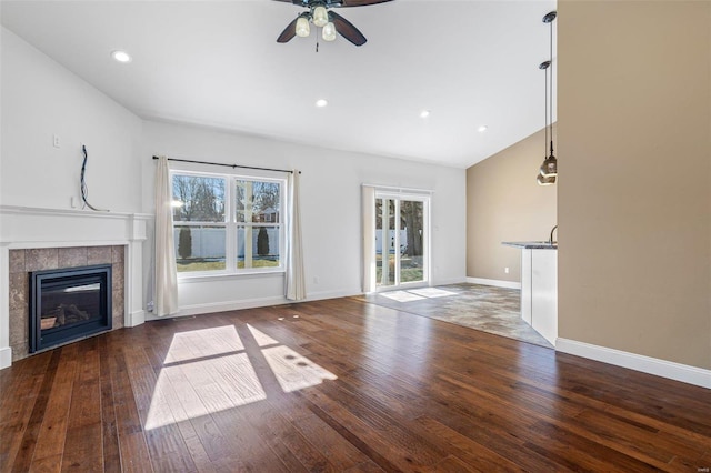 unfurnished living room featuring ceiling fan, dark wood-type flooring, and a fireplace