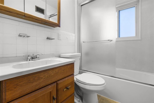 full bathroom featuring vanity, decorative backsplash, tile walls, toilet, and combined bath / shower with glass door