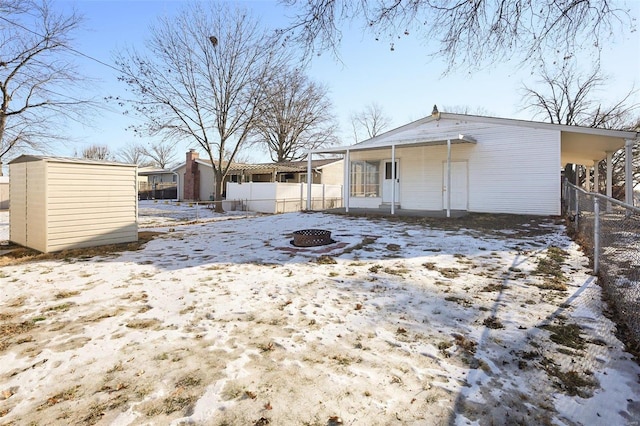 snow covered property featuring covered porch and a storage shed