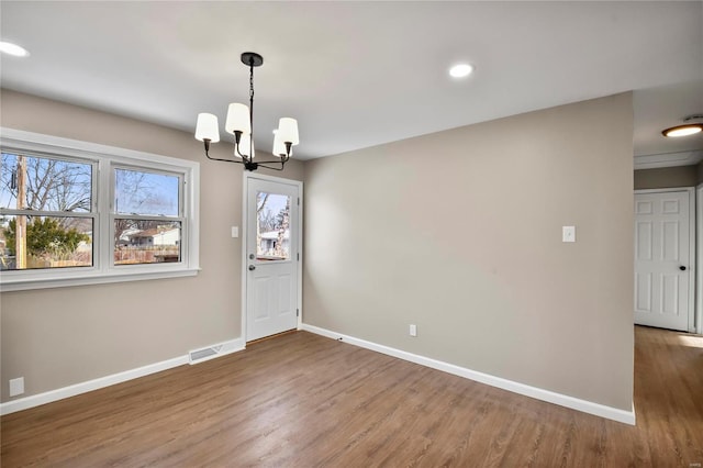 unfurnished dining area with a notable chandelier and wood-type flooring