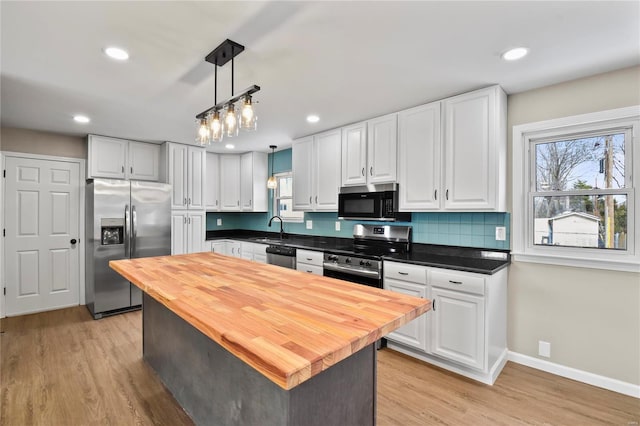 kitchen featuring pendant lighting, white cabinets, a center island, stainless steel appliances, and light hardwood / wood-style flooring