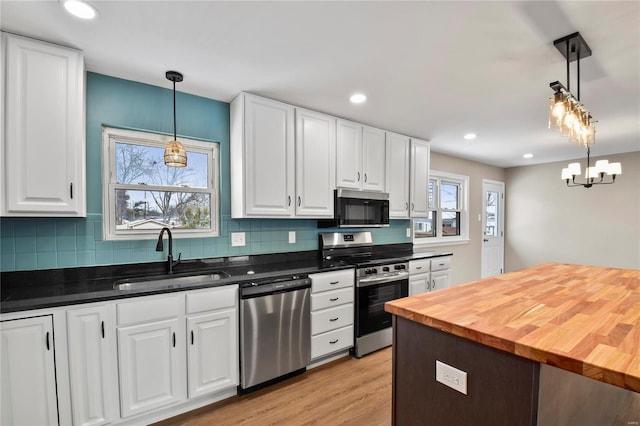 kitchen with pendant lighting, white cabinetry, stainless steel appliances, and sink