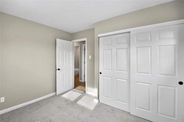 unfurnished bedroom with light colored carpet and a closet