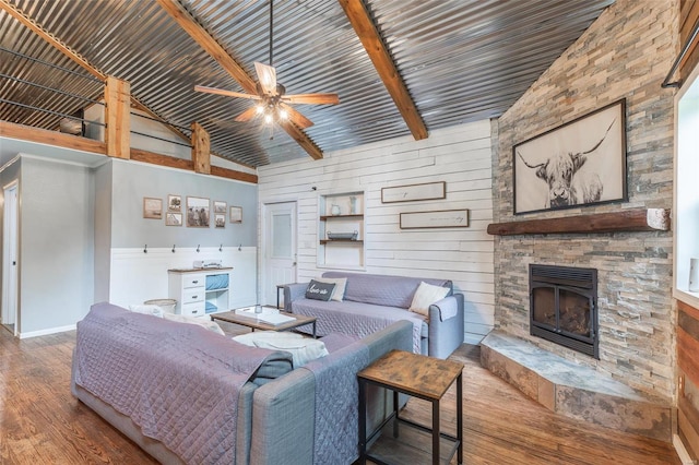 living room featuring beam ceiling, wood-type flooring, wood walls, and a fireplace