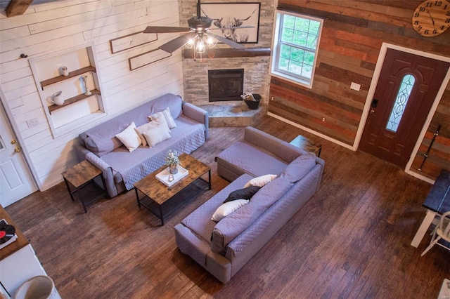 living room featuring a fireplace, dark hardwood / wood-style flooring, ceiling fan, and wooden walls