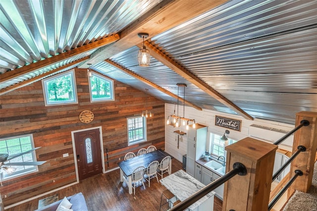 living room featuring dark wood-type flooring, a wealth of natural light, wood walls, and lofted ceiling with beams