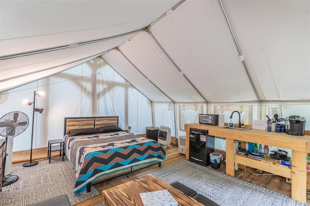 bedroom featuring vaulted ceiling, hardwood / wood-style floors, and sink