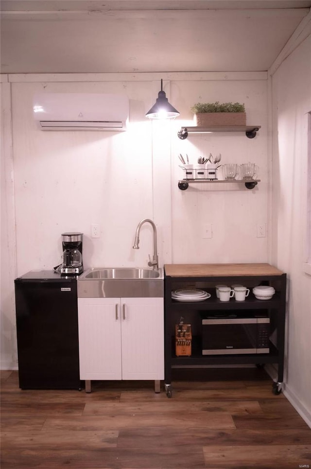 bar with dark hardwood / wood-style floors, pendant lighting, sink, a wall mounted air conditioner, and white cabinets