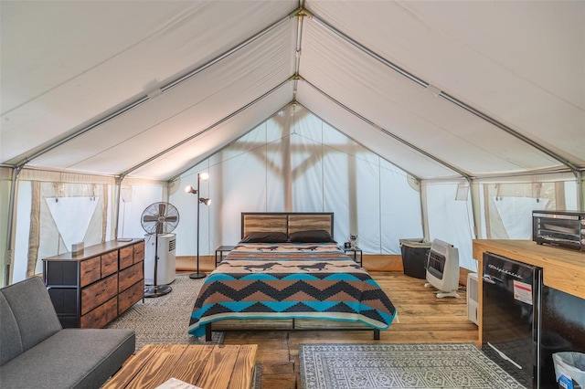 bedroom with lofted ceiling, refrigerator, and heating unit