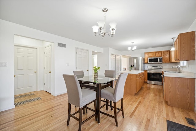 dining room featuring sink, light hardwood / wood-style flooring, and a notable chandelier