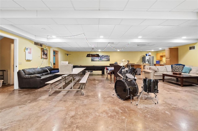 game room with a paneled ceiling and concrete flooring