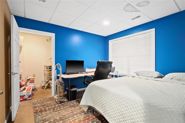 carpeted bedroom featuring a drop ceiling