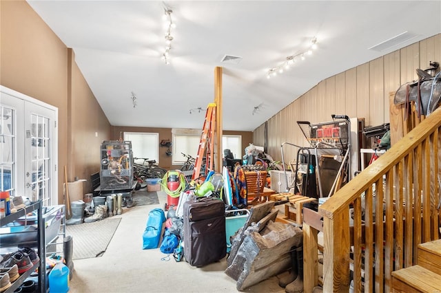 misc room featuring lofted ceiling, carpet floors, rail lighting, and wooden walls