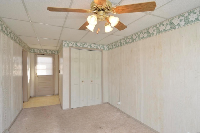 unfurnished bedroom featuring a drop ceiling, a closet, and ceiling fan