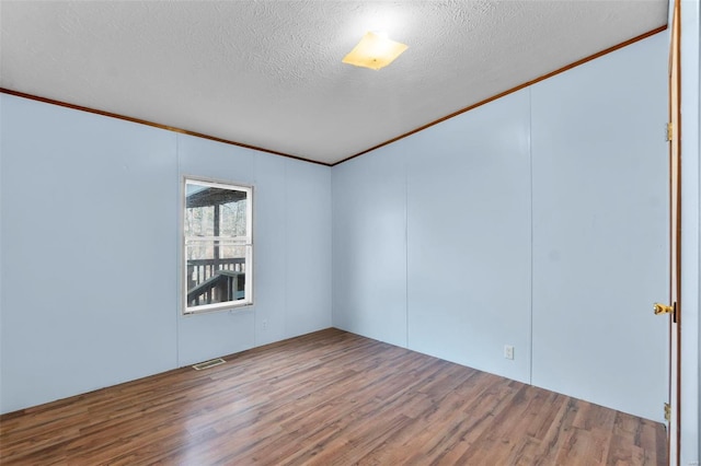 spare room featuring ornamental molding, hardwood / wood-style floors, and a textured ceiling