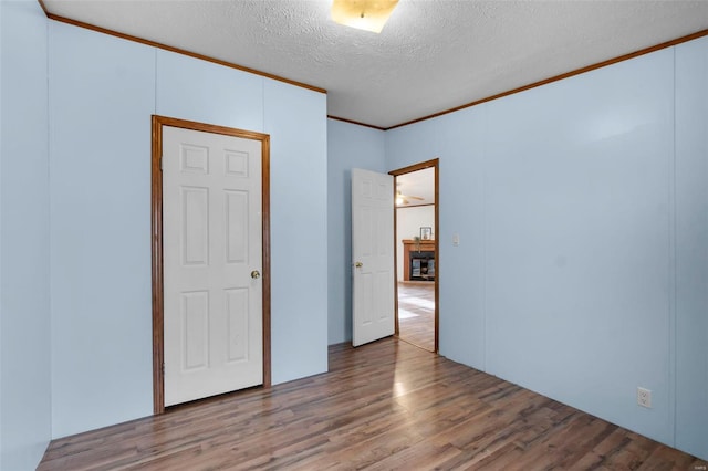 spare room with ornamental molding, wood-type flooring, and a textured ceiling