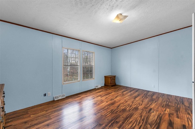 empty room featuring crown molding, dark hardwood / wood-style floors, and a textured ceiling