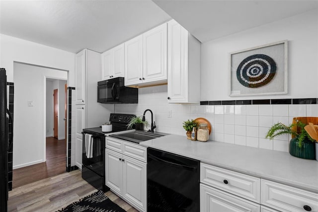 kitchen with sink, white cabinetry, tasteful backsplash, light wood-type flooring, and black appliances