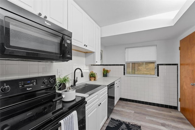 kitchen featuring sink, light hardwood / wood-style flooring, white cabinets, and black appliances