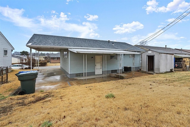 rear view of house with a shed, a yard, a carport, and central air condition unit