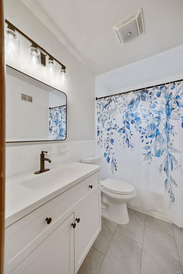 bathroom with tile walls, vanity, tile patterned flooring, and toilet