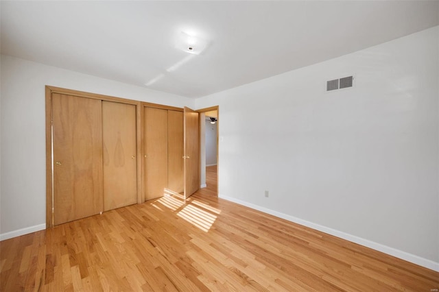 unfurnished bedroom with multiple closets and light hardwood / wood-style flooring