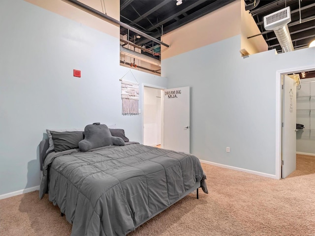 bedroom featuring a walk in closet, carpet floors, and a high ceiling