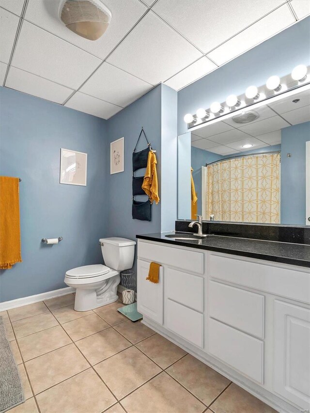 bathroom with tile patterned flooring, vanity, a paneled ceiling, and toilet