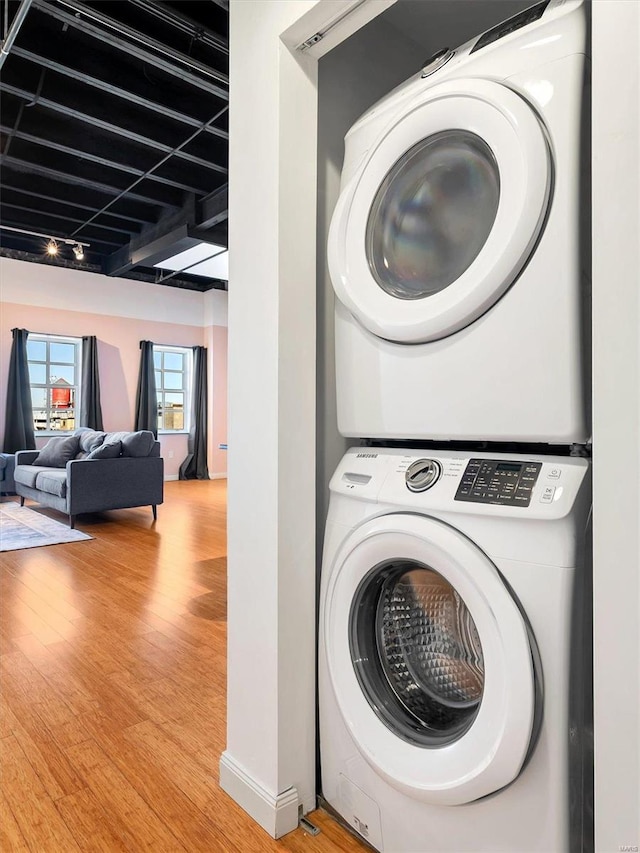 clothes washing area featuring stacked washer / dryer and light hardwood / wood-style floors