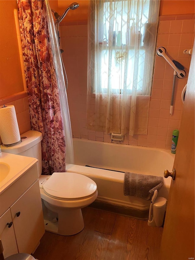 full bathroom with tile walls, hardwood / wood-style floors, toilet, vanity, and shower / bathtub combination with curtain