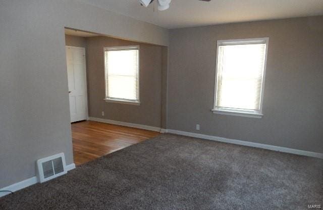 carpeted spare room featuring ceiling fan and a wealth of natural light