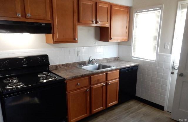 kitchen featuring black appliances, dark wood-type flooring, and sink