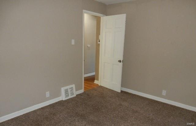 spare room featuring dark colored carpet