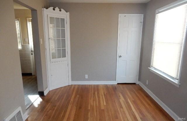 empty room featuring wood finished floors, visible vents, and baseboards