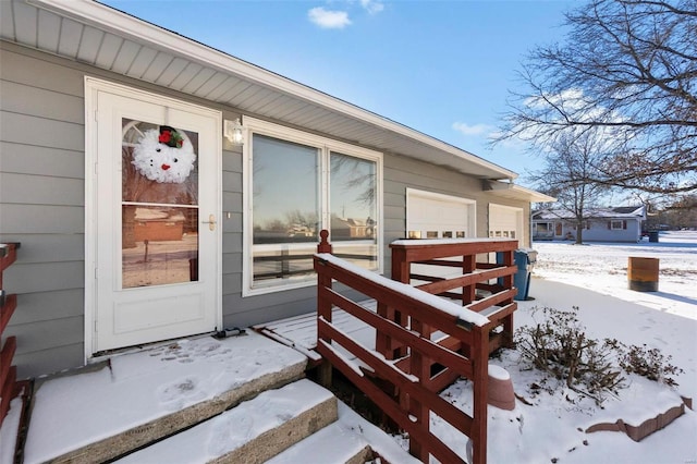 snow covered property entrance with a garage