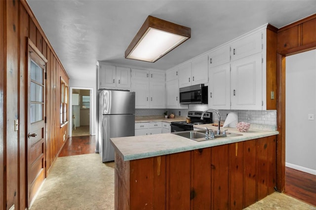 kitchen with decorative backsplash, white cabinets, sink, kitchen peninsula, and stainless steel appliances