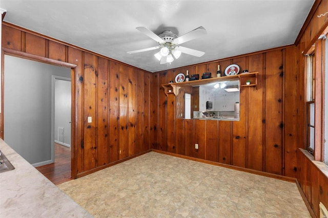 spare room featuring crown molding, wooden walls, and ceiling fan